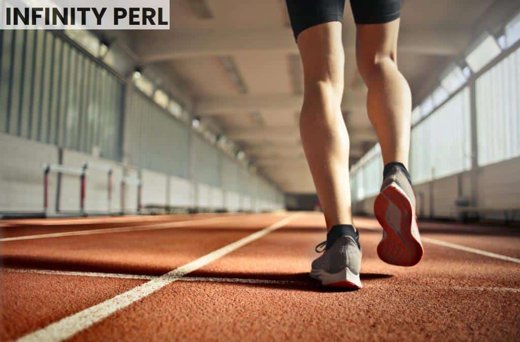 From below back view of crop strong runner walking along running track in athletics arena while doing warm up exercises during workout