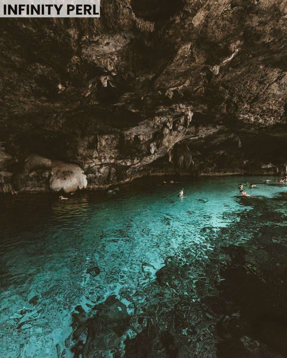 photography of people swims on body of water with cave